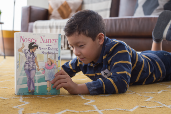 A young boy is reading a book on the floor.