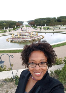 A woman with curly hair smiling and taking a selfie